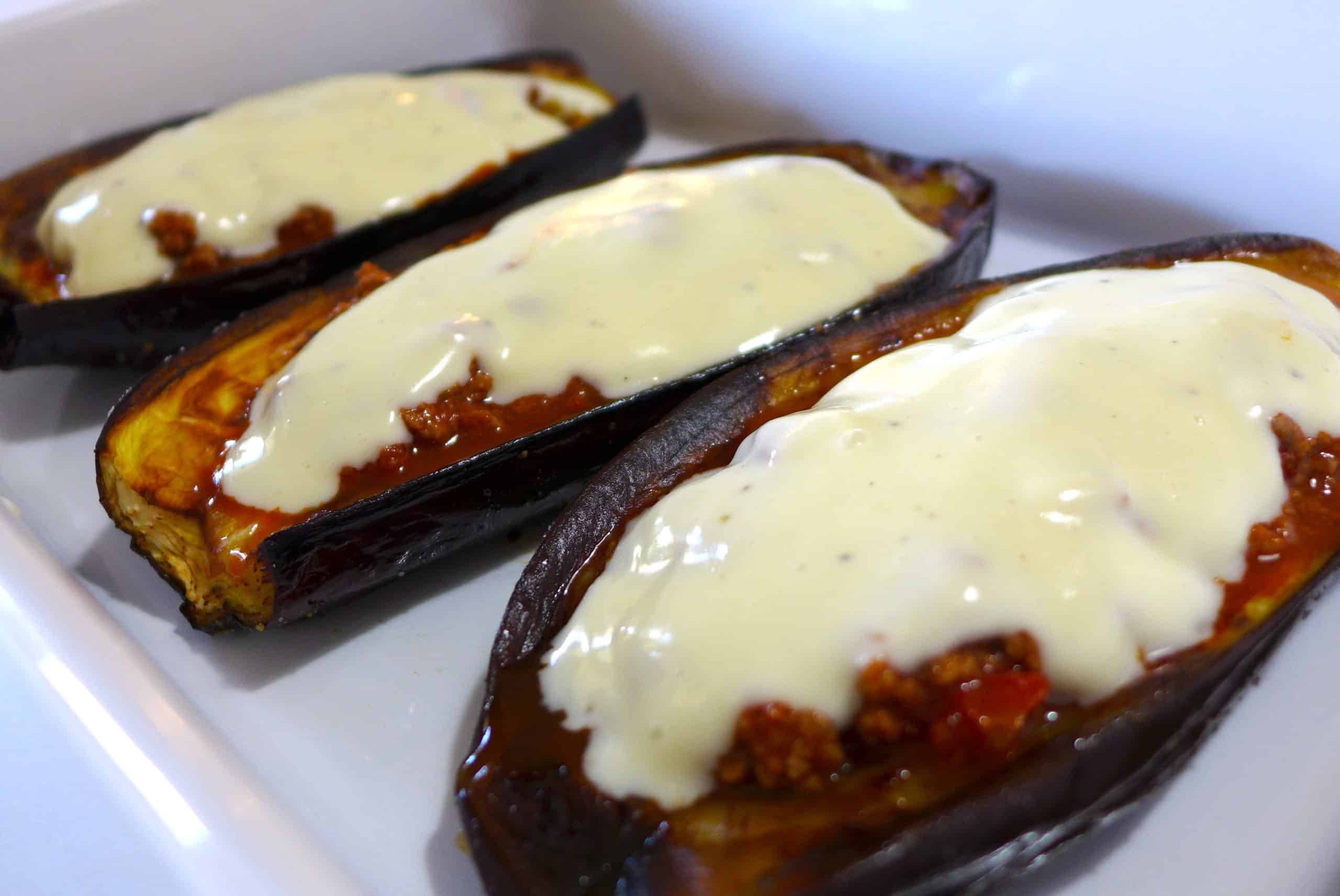 greek stuffed eggplant in a white casserole dish topped with creamy Béchamel sauce and mashed potatoes